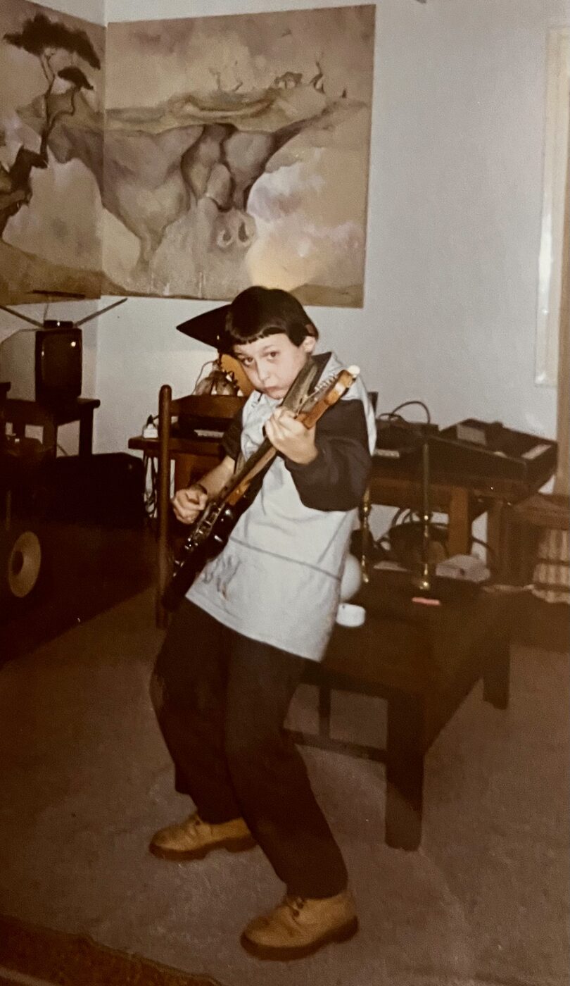 Thanos at nine, playing electric guitar in his childhood music setup