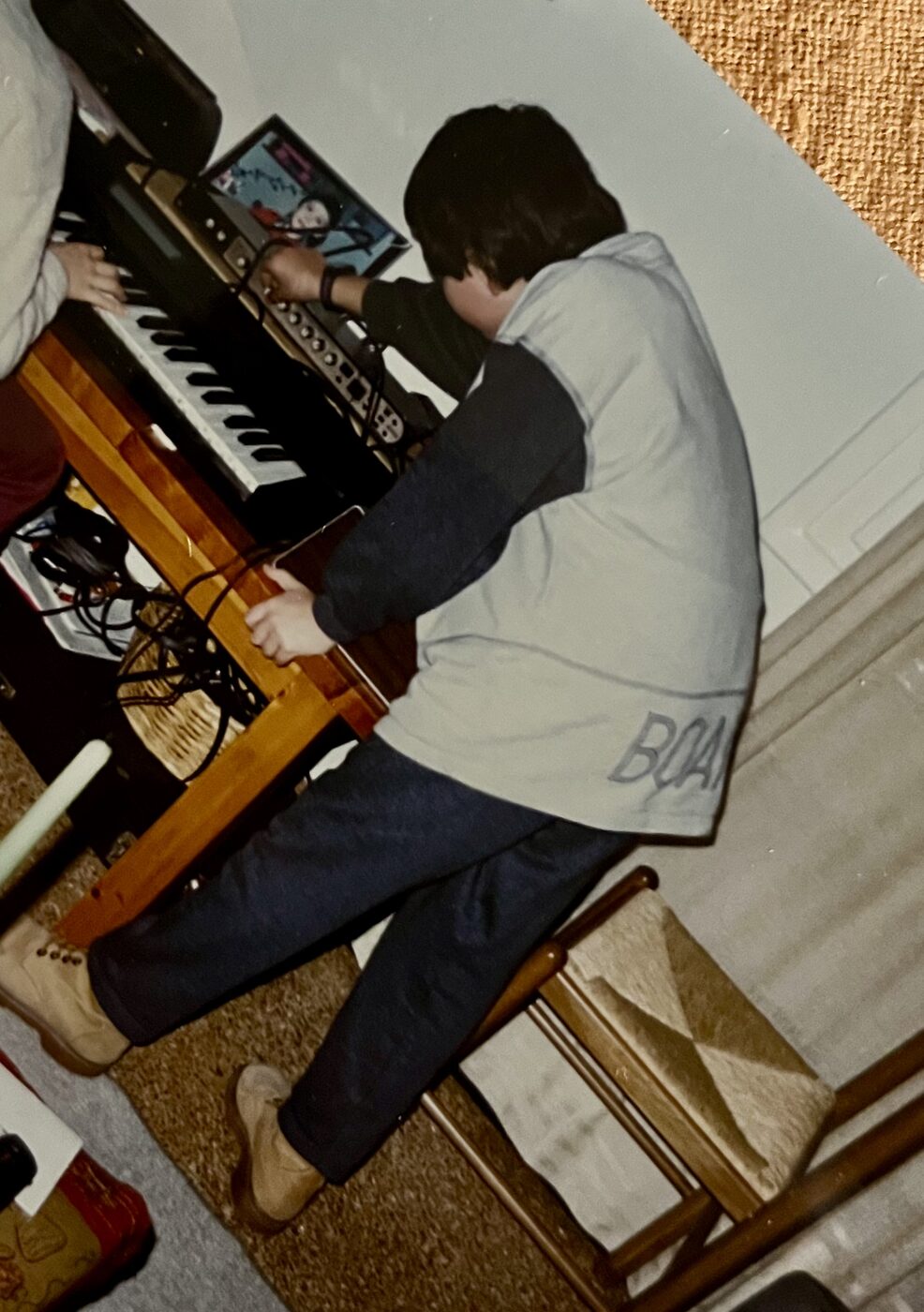 Thanos at nine, adjusting a synthesizer while holding a guitar