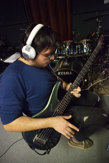 Thanos performing live on bass under red stage lights in 2017