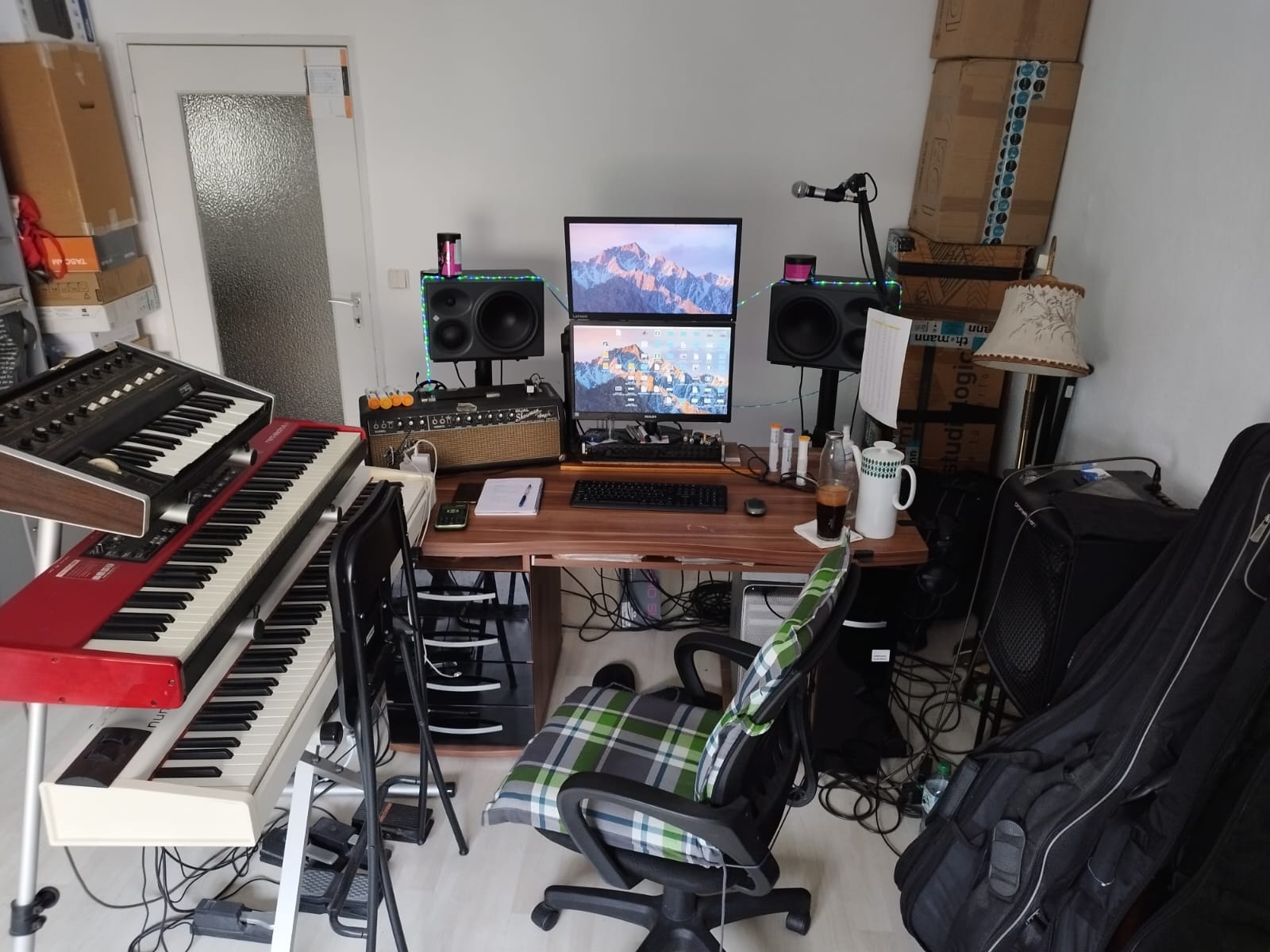 Thanos's home studio workspace with keyboards, monitors, guitars, and computer